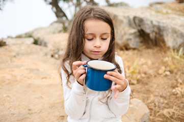 Young girl enjoying hot drink outdoors in nature on a hike
