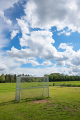 metal soccer goal on a green lawn. outside on the outskirts of town. blue sky with clouds.