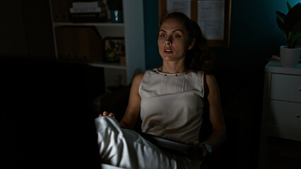 Obraz premium A young woman in a dimly lit office, looking surprised or alarmed, providing a sense of drama or suspense.