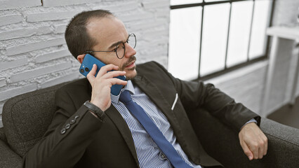 Bald professional man in suit on phone in office setting, exuding confidence and focus.