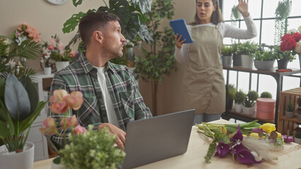 A man and a woman working together in a vibrant indoor flower shop surrounded by lush plants and colorful blooms.