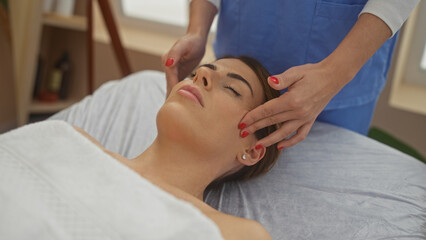 A woman receiving a relaxing massage from a therapist in a wellness center, showcasing a serene indoor spa environment with a focus on beauty and relaxation.