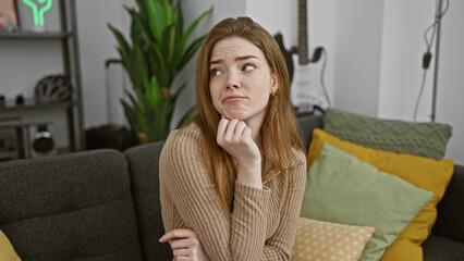 Pensive young caucasian woman in a cozy living room with modern decor