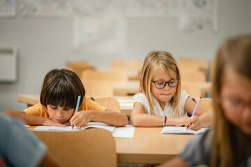 Young students do tasks and write on notebook on the class