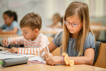 Young students do tasks and write on notebook on the class