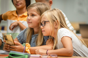 Young students use cellphone for video games on a break at school