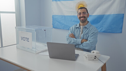 Young man with mustache and glasses in voting room with argentinian flag in background, seated with...