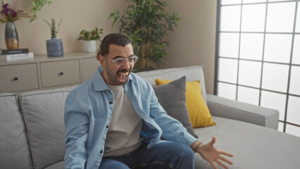 Young man with moustache excitedly reacting in a modern living room filled with indoor plants and...