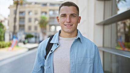 Fototapeta premium Portrait of a smiling young hispanic man in casual attire standing on a city street
