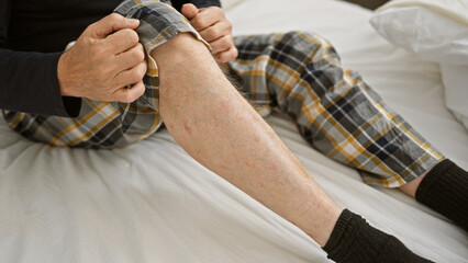 A middle-aged man in pajamas sits on a bed in a neutral-toned bedroom, suggesting relaxation or preparing for sleep.
