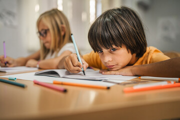 Young students do tasks and write on notebook on the class