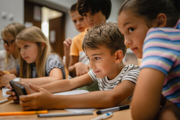Young students use cellphone for video games on a break at school