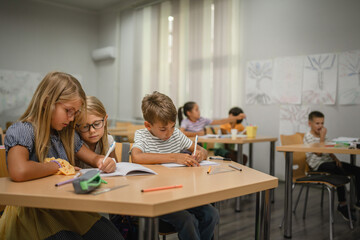 Young friends student do tasks and write on notebook on the class