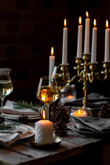 Elegant decor for Christmas family dinner. Center piece with burning candles, vintage chandelier. Zero waste eco-friendly reusable home decoration, fir tree branches. Cozy atmosphere, wooden furniture