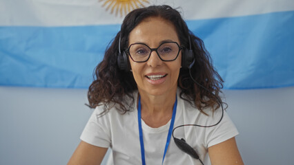 Woman smiling while wearing a headset and sitting in front of an argentinian flag during an indoor...