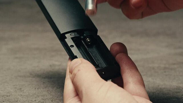 Adding silver batteries AA and AAA in remote controller TV close-up. Batteries are common in portable electronic devices. An AA battery is composed of a single electrochemical cell that may be either