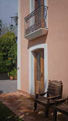 A quaint, sunlit spanish villa with a decorative balcony, terracotta tiles, and wooden bench evoking a peaceful ambiance.