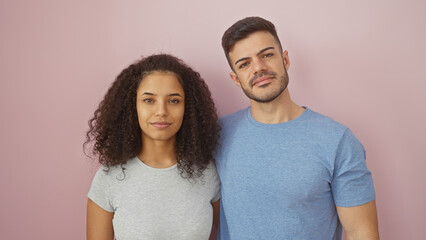 A multicultural couple stands together against a pink background, conveying love and unity.