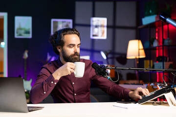 ASMR artist using high tech quality mic in studio to do anti stress video, drinking coffee to make tingling slurping sounds. Man using professional microphone to get sleep inducing high quality audio