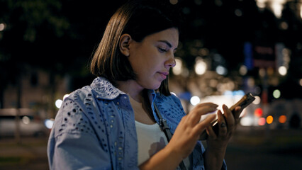 Young beautiful hispanic woman smiling happy using smartphone in the streets at night