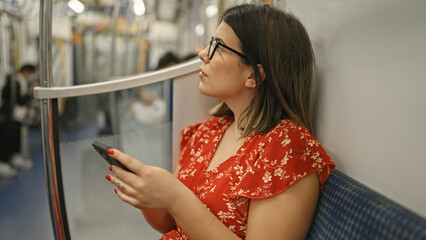 Captivating portrait of a beautiful young hispanic woman donning glasses, engrossed in her phone as...