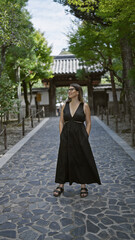 Naklejka premium Cheerful young hispanic woman, effortlessly beautiful with glasses, confidently posing and joyfully smiling while exploring the serene surroundings of ginkaku-ji temple, kyoto, japan