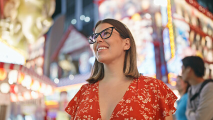 Obraz premium Capturing the joyful night, beautiful hispanic woman in glasses enjoying shinsekai street, laughter dancing in her eyes as she takes in the osaka city lights