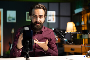 Tech guru presenting V mount battery, filming technology review using cellphone on tripod and...