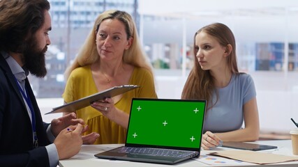 Clients looking over personalized planning guide on green screen laptop written by financial advisor during meeting. Consultant optimizing living expenses for customers using mockup notebook, camera B