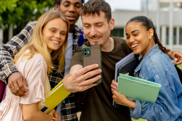 multiracial group of young college or high school students taking a selfie picture with a smartphone after class.