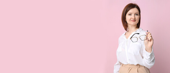 Young pretty businesswoman with eyeglasses on pink background
