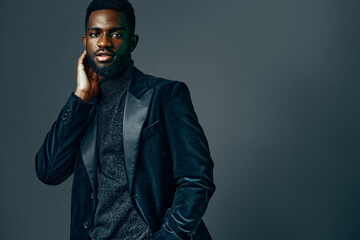Obraz premium Stylish african american man in black suit and turtleneck posing confidently for camera in urban setting