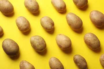 Many fresh potatoes on yellow background, flat lay