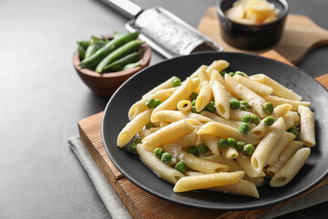 Delicious pasta with green peas, cheese and grater on grey table