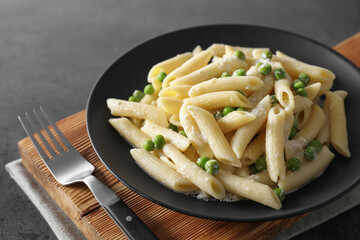 Delicious pasta with green peas, cheese and fork on grey table