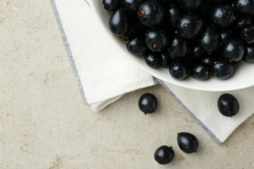Ripe black currants in bowl on light table, top view. Space for text