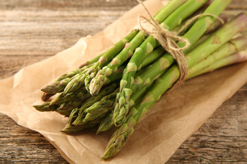 Bunch of fresh green asparagus stems on wooden table, closeup