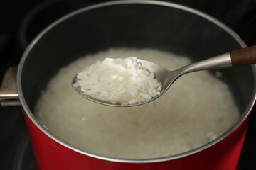 Taking boiled rice from pot with spoon, closeup
