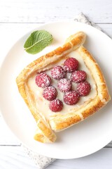 Tasty puff pastry with raspberries on white wooden table, top view