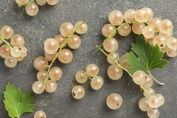 Fresh white currant berries and green leaves on gray textured table, flat lay