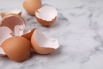 Broken eggshells on light marble table, closeup. Space for text