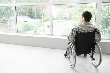 Young soldier in wheelchair at home, back view