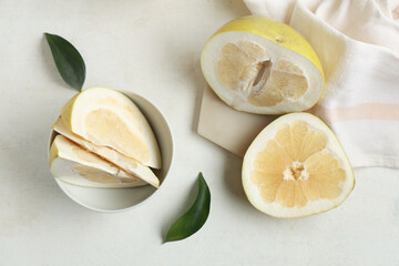 Bowl and board of cut fresh pomelo fruit on white background