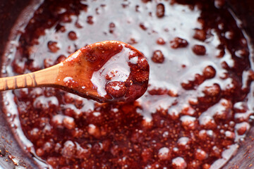 Making strawberry jam at home. Wild strawberry jam is boiled in a saucepan and stirred with a...