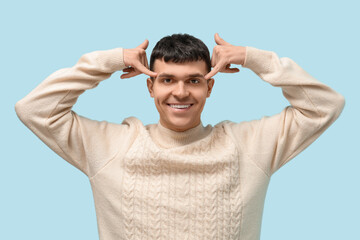 Naklejka premium Young deaf mute man using sign language on blue background