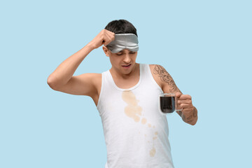 Confused man with coffee stains on his sleeveless shirt on blue background