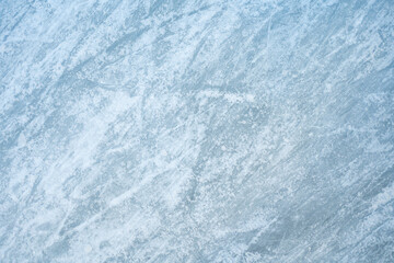 Icy background on rink with visible traces of skating, showcasing the essence of winter sport. Texture of ice on skating rink visible from top view, displaying sheet of scratched ice.