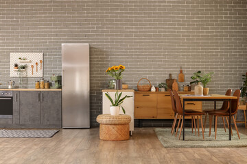 Interior of modern comfortable kitchen with fridge, counter and dining table