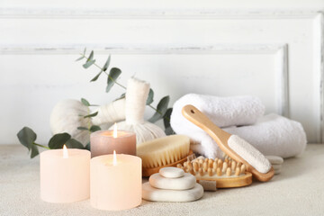 Glowing aroma candles with spa supplies on light background