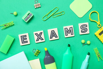 Composition with word EXAMS and different stationery on green background